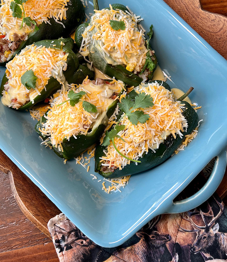 Elk stuffed poblano peppers with cornbread topping served with salsa and avocado